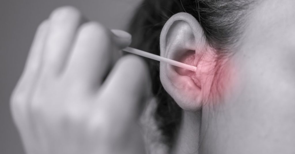 woman sticking cotton swab in her ear
